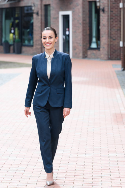 beautiful businesswoman walking on street and looking away - Fotoğraf, Görsel