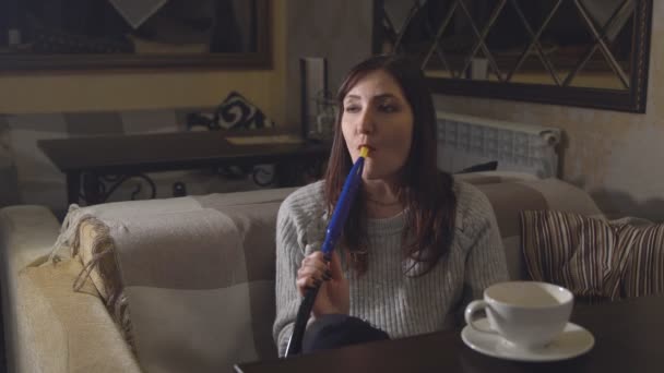 brünette Frau in einem Café qualmt aus einer Wasserpfeife - Filmmaterial, Video