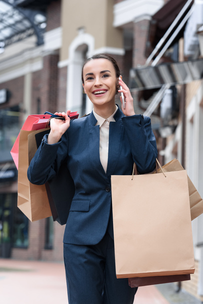 attractive businesswoman walking form shopping and talking by smartphone - Foto, Bild