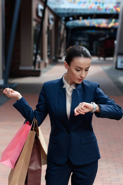 красивая деловая женщина проверяет время в торговом центре
 - Фото, изображение