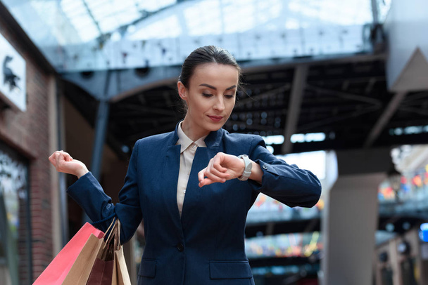 attractive businesswoman checking time in shopping mall - Foto, imagen