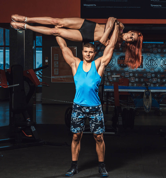 atlético hombre levanta chica fitness como peso sobre sí mismo en el gimnasio
 - Foto, imagen