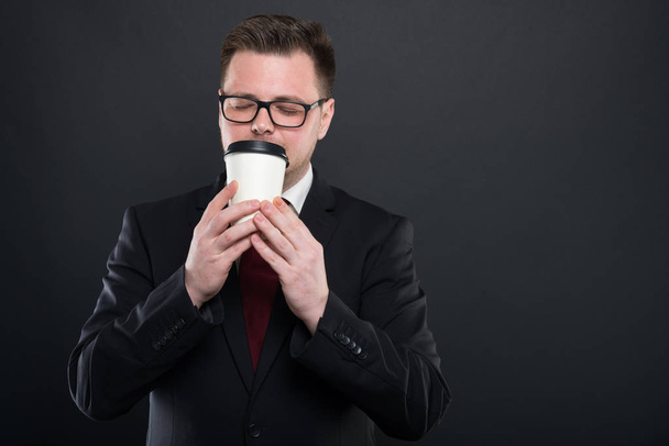 Portrait of business man smelling cup of takeaway coffe - Photo, image