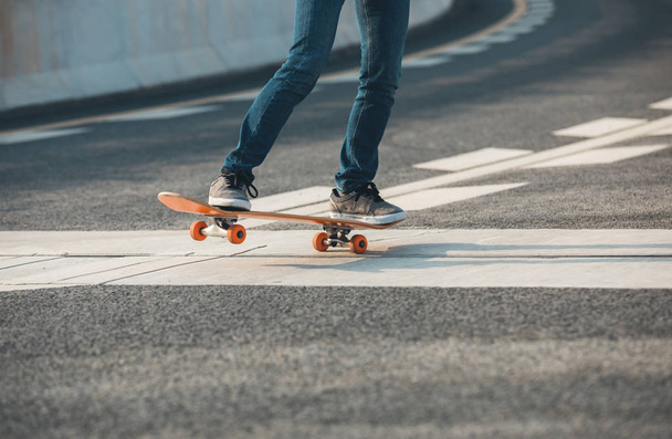 Cropped image of skateboarder sakteboarding on highway - Photo, Image