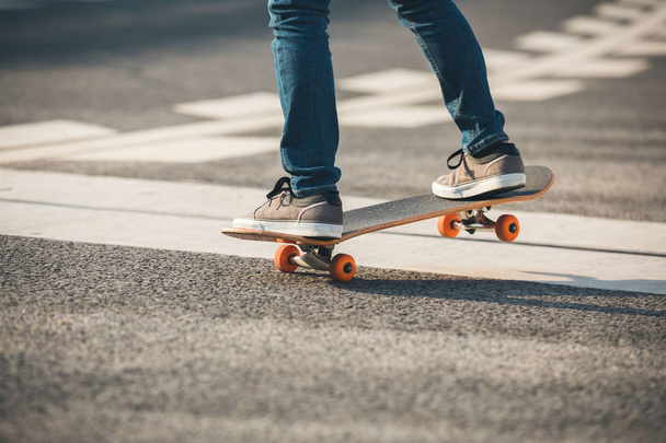 Cropped image of skateboarder sakteboarding on highway - Foto, afbeelding