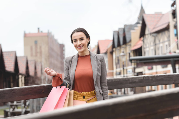 attractive woman standing with shopping bags on bridge - Fotografie, Obrázek