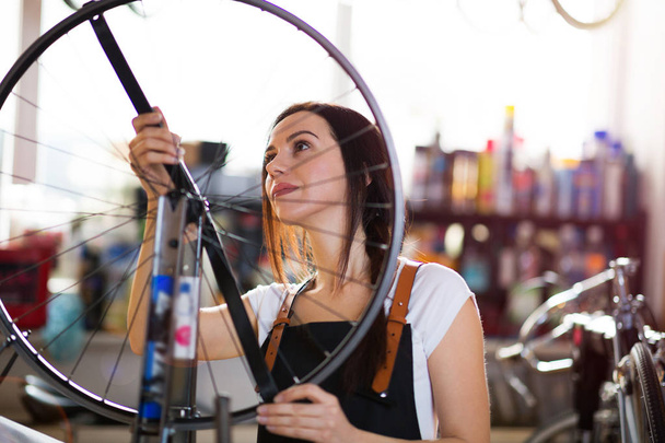 Young woman working in a bicycle repair shop - Fotografie, Obrázek