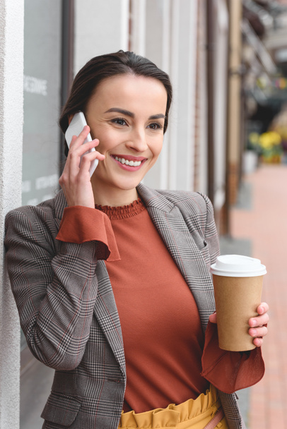 szép stílusos nő beszél a smartphone és a gazdaság kávé papírpohár - Fotó, kép