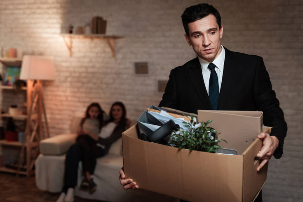 frustrierter Geschäftsmann hält Schachtel mit Dingen und verlässt seine Familie - Foto, Bild