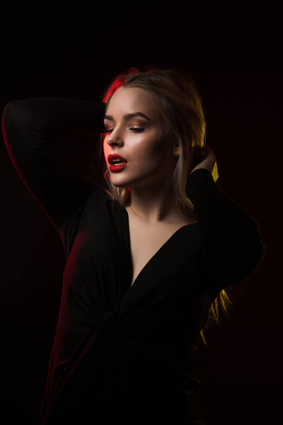 modisches junges Model mit hellem Make-up posiert über einem dunklen Ba - Foto, Bild