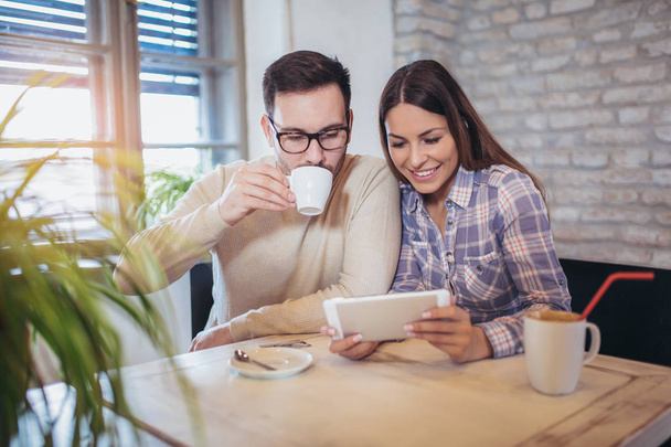 Couple souriant utilisant une tablette numérique et boire du café à la maison
 - Photo, image