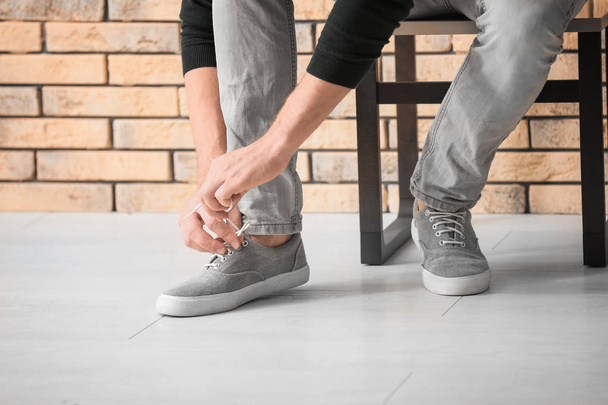 Man tying shoelaces indoors - Zdjęcie, obraz