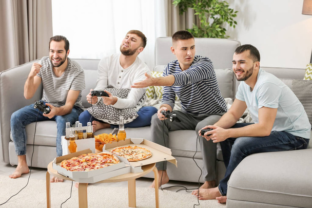 Young men playing video games at home - Foto, afbeelding