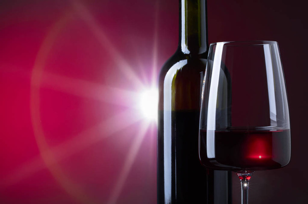 Glas und Flasche Rotwein auf dunklem Hintergrund.  - Foto, Bild