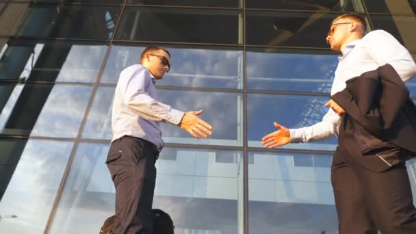 Two businessmen meeting near office and greeting each other. Colleagues shake hands in the urban environment. Business handshake outdoor. Shaking of male arms outside. Close up Slow motion - Footage, Video