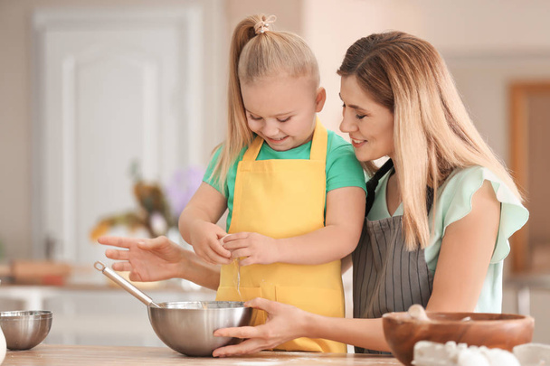 Mother with daughter preparing dough together in kitchen - Foto, imagen