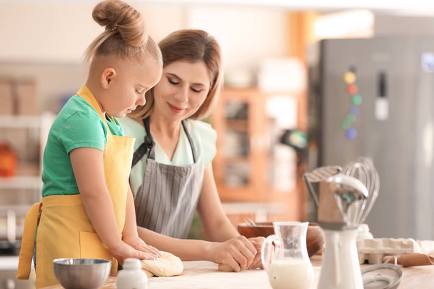 Mother and daughter with dough at table in kitchen - Photo, image