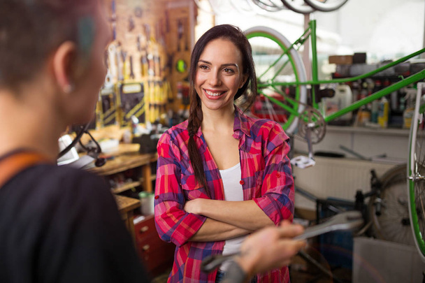 Two young women working in a bicycle repair shop - Foto, Imagem