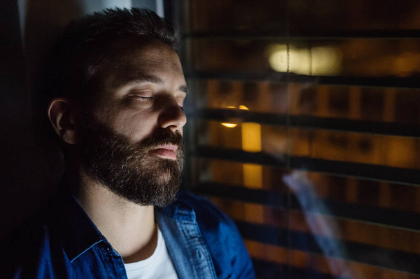 A man slepping by the window at home at night. - Φωτογραφία, εικόνα