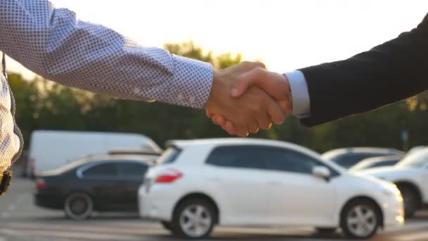 スーツを着た男性の手が彼の友人に車の鍵を与える。ビジネスマンの腕は車のキーを渡します。2人のビジネスマンの間で握手。スローモーションを閉じます - 映像、動画