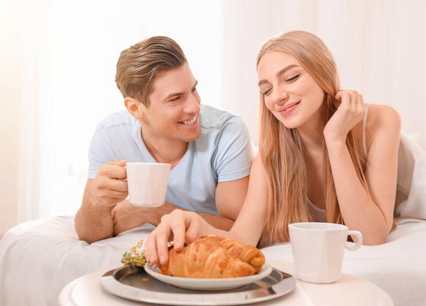 Young lovely couple having breakfast on bed - Foto, afbeelding