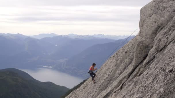 Anténa z kavkazské americká žena horolezec jištění dolů na skalnaté extrémní tvář venku v Kanadě Squamish údolí - Záběry, video