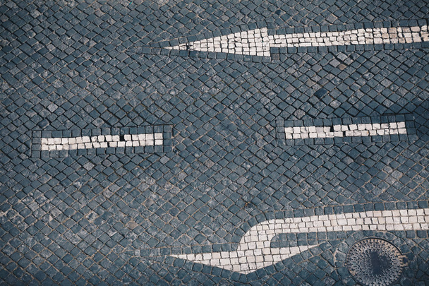Направление стрелка и уличный знак на каменном тротуаре ручной работы в Лиссабоне - традиционный португальский ручной мозаичный фон
 - Фото, изображение