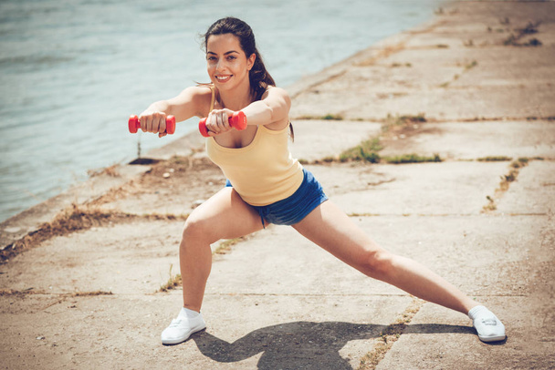 Jeune femme de fitness faisant de l'exercice avec haltères par la rivière
 - Photo, image