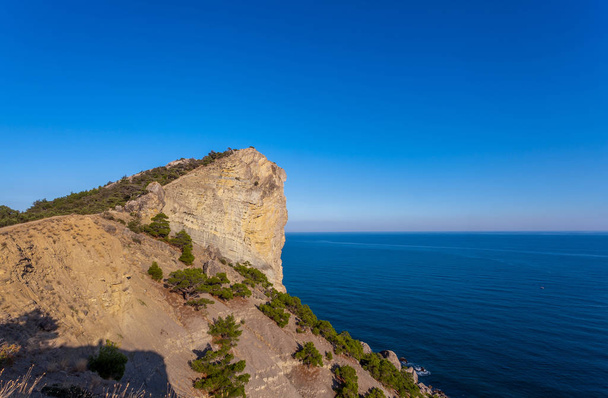 Vista sobre una enorme roca cubierta con pocos árboles pequeños sobre el mar Negro
 - Foto, Imagen
