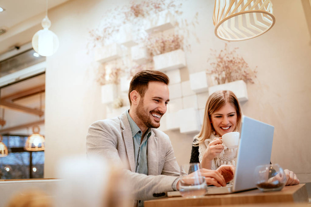zwei schön lächelnde Geschäftsleute, die in der Pause im Café am Laptop arbeiten - Foto, Bild
