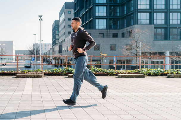 νεαρός άνδρας που τρέχει υπαίθρια εκπαίδευση στην πόλη - άσκηση, υγιεινό τρόπο ζωής, έννοια του αθλητισμού - Φωτογραφία, εικόνα