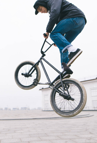 BMX freestyle close up. A young man makes stunts on a BMX bike.Street culture - Photo, Image
