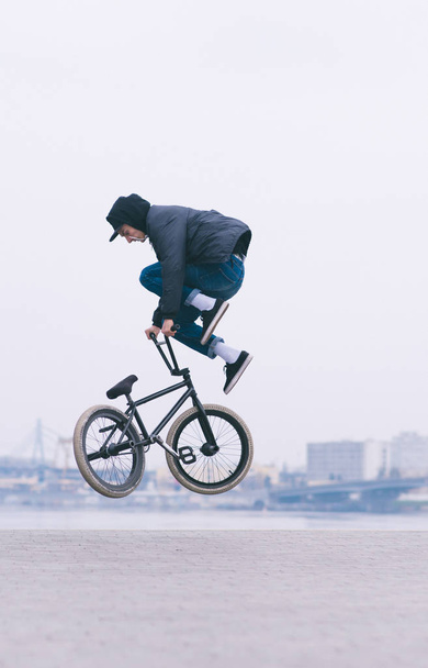 BMX вільний стиль. Молодий чоловік робить повітряні трюки на велосипеді BMX. На тлі міського пейзажу
 - Фото, зображення