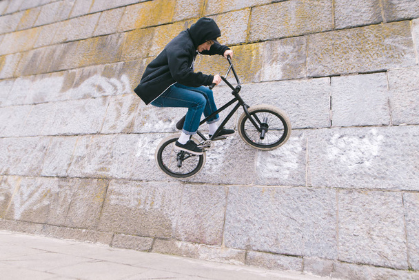 BMX rider biciklivel megy a falra. Egy fiatal férfi csinál Bmx. Bmx Freestyle trükkök - Fotó, kép