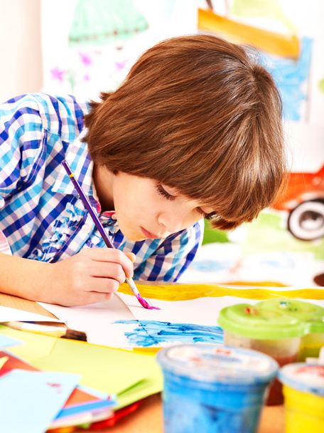Child painting at easel. - 写真・画像
