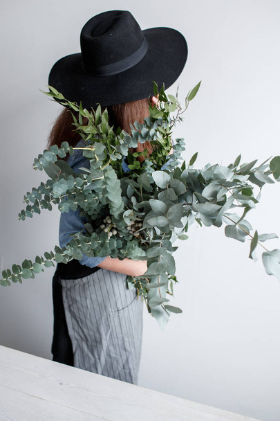Florist makes a bouquet. Process of work. woman holding a bouquet of eucalyptus in hands - Foto, Imagen