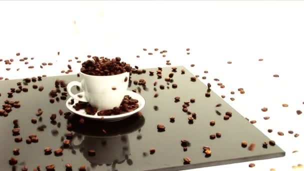 κόκκους καφέ ρίχνει στο λευκό φλιτζάνι καφέ & πιατάκι - Πλάνα, βίντεο