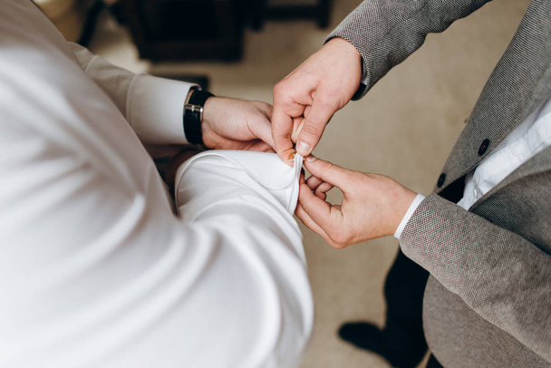Cropped view of groomsman helping groom with cufflinks on shirt - Foto, Imagen