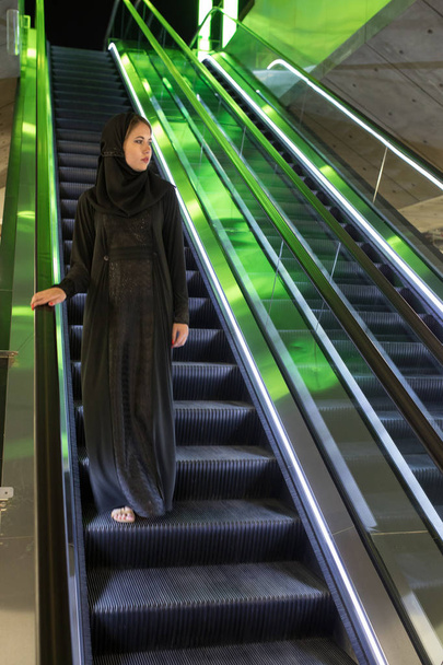 Muslim woman wearing in a hijab descends the escalator. - Foto, afbeelding