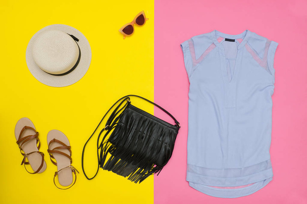 Garde-robe féminine. Top bleu, sac à main, sandales et chapeau. Fond rose et jaune
 - Photo, image