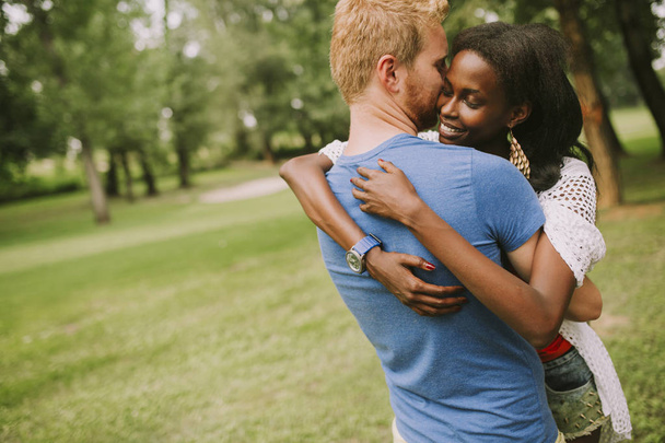 Gelukkige jonge mooie multiraciale paar in het park op een zomerdag - Foto, afbeelding