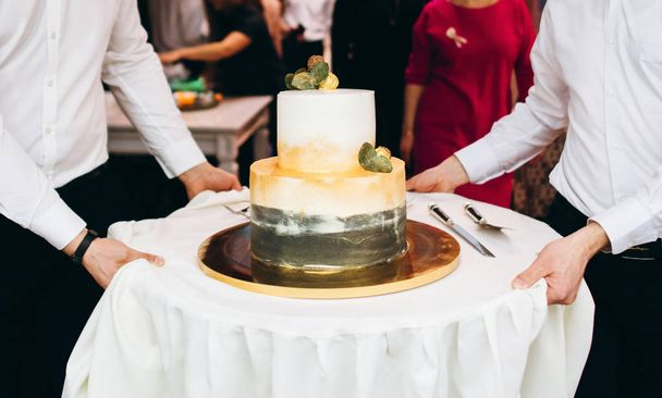 Σερβιτόροι εξυπηρετούν τραπέζι των διακοπών με γαμήλια τούρτα - Φωτογραφία, εικόνα