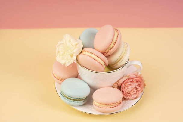 Multicolored macaroons cake are placed in a saucer and a cup alo - Valokuva, kuva