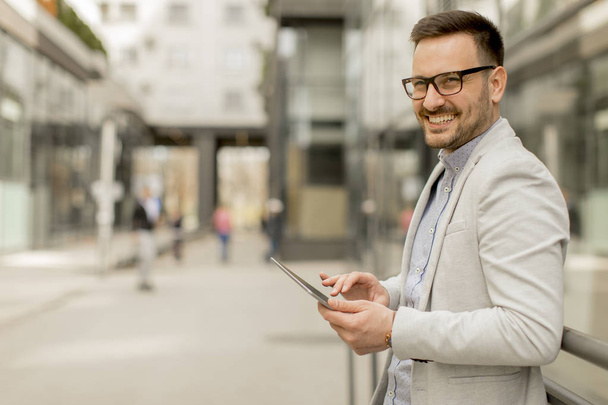 Handsome young businessman with digital tablet by the office building - Foto, Imagem