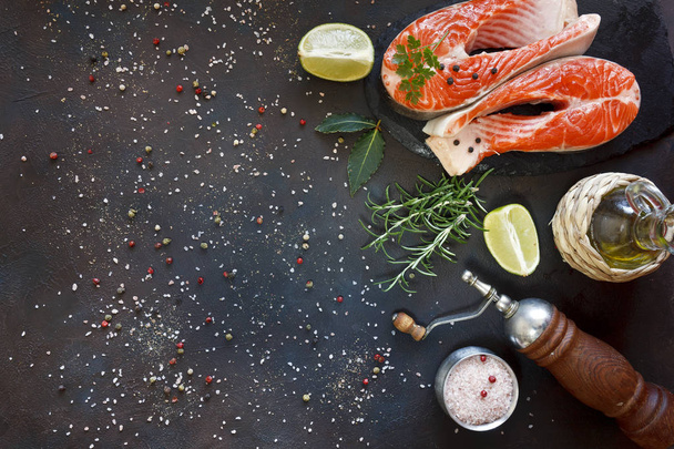 close-up photo of fresh salmon fish with lime slices and rosemary on black table background - Foto, imagen