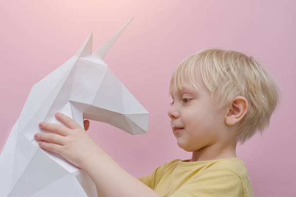 White paper unicorn and little blonde boy. Pink background. - Photo, Image
