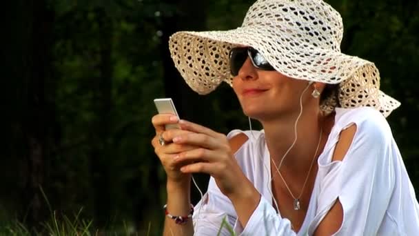 Mujer joven acostada en el parque escuchando música
 - Metraje, vídeo