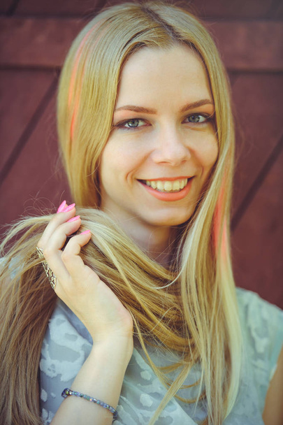 Houkutteleva vaatimaton nuori vaalea nainen leikkii hiukset punaisella puupohjalla hänen hiukset maalattu vaaleanpunainen raidallinen raidallinen, sininen mekko ujo ja utelias
 - Valokuva, kuva