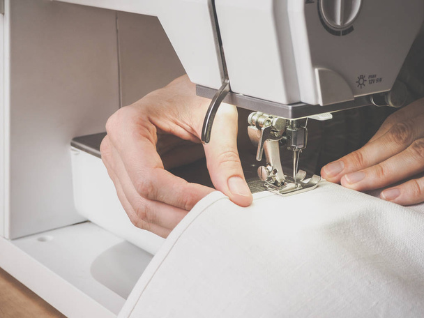 Proceso de costura primer plano en la máquina de coser. El prensatelas y la aguja de la máquina de coser durante el funcionamiento
. - Foto, imagen