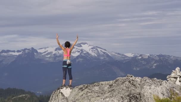 Aerial Caucasian American female adventure climber celebrating achieving success with raised hands on peak of Mount Habrich Canada - Footage, Video